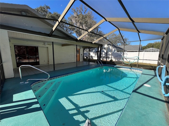 view of pool with glass enclosure, a patio area, and ceiling fan