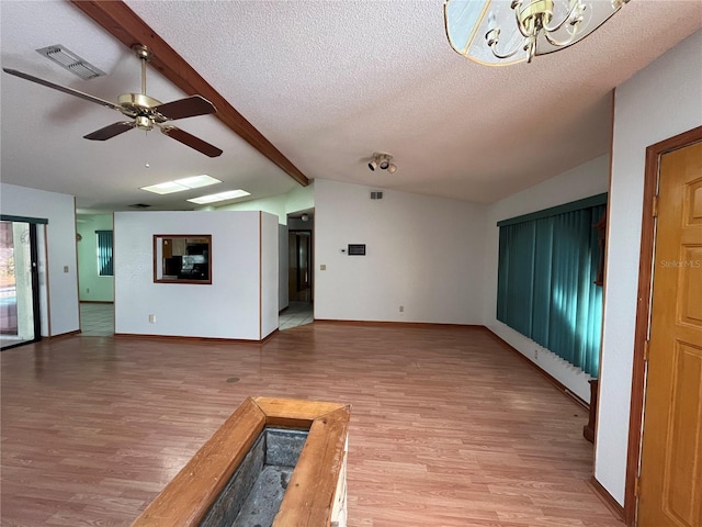 unfurnished living room featuring ceiling fan, lofted ceiling with beams, a textured ceiling, and hardwood / wood-style floors