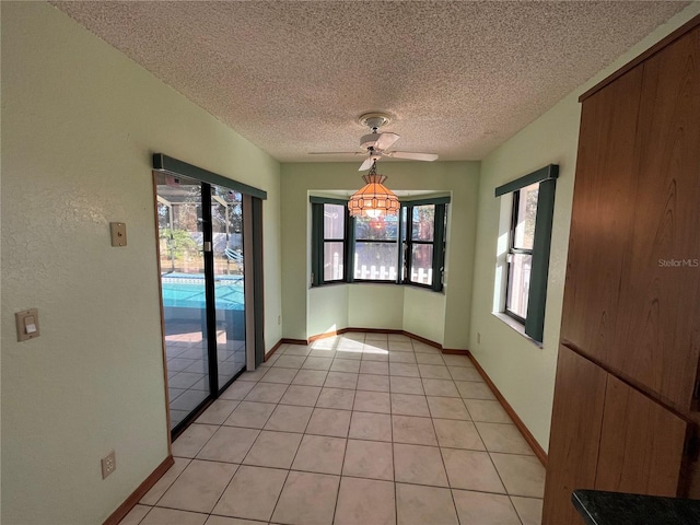 unfurnished dining area with ceiling fan, light tile patterned floors, and a textured ceiling