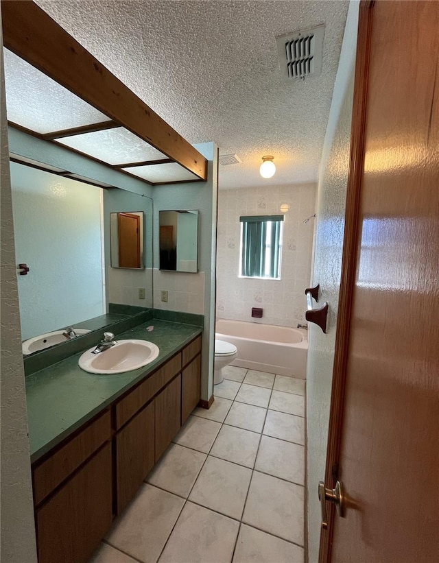 full bathroom featuring tile patterned flooring, toilet, tiled shower / bath, a textured ceiling, and vanity