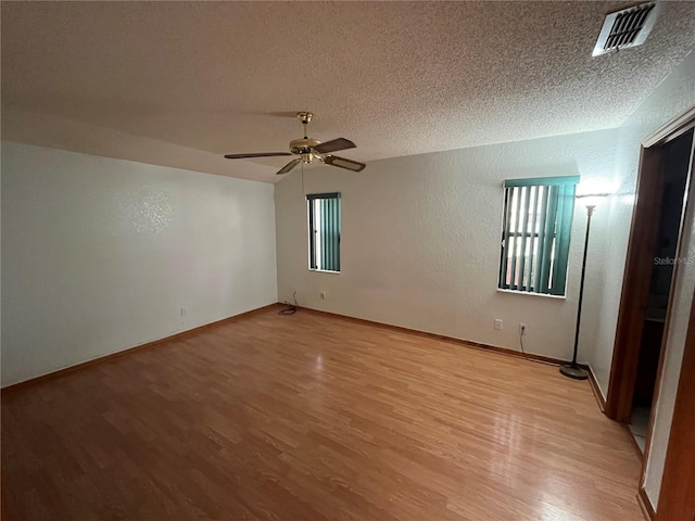 spare room featuring light hardwood / wood-style floors, ceiling fan, and a textured ceiling