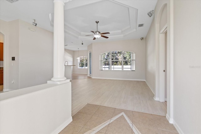 interior space featuring a raised ceiling, light hardwood / wood-style floors, and ornate columns