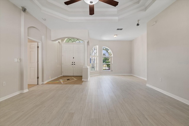 foyer with ceiling fan, a raised ceiling, light wood-type flooring, and ornamental molding