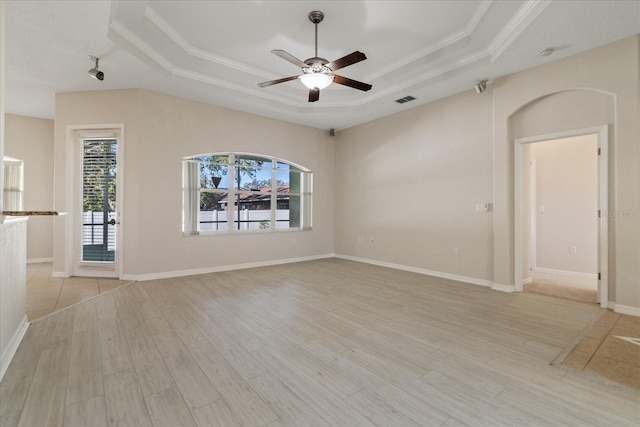 unfurnished living room featuring a raised ceiling, ceiling fan, crown molding, and light wood-type flooring