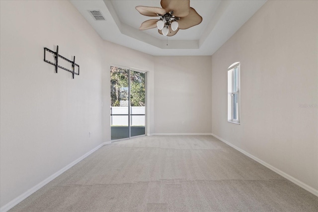 carpeted empty room with a tray ceiling and ceiling fan