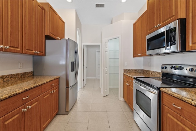 kitchen with light stone counters, light tile patterned floors, and stainless steel appliances