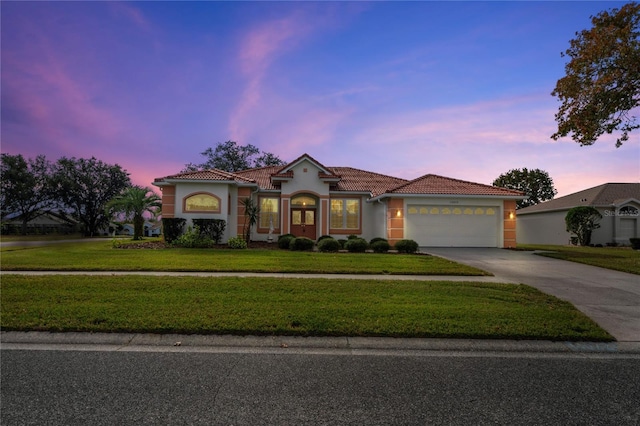 mediterranean / spanish-style house featuring a yard and a garage