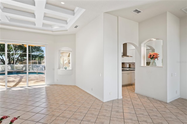 tiled spare room featuring a towering ceiling and coffered ceiling