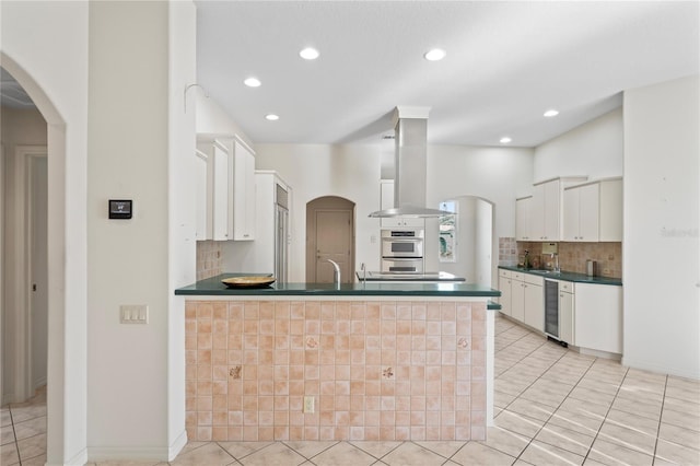 kitchen with ventilation hood, white cabinetry, and kitchen peninsula