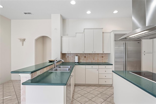 kitchen with white cabinets, stainless steel built in fridge, sink, decorative backsplash, and island exhaust hood