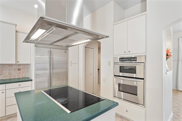 kitchen with island exhaust hood, light tile patterned floors, stainless steel appliances, and white cabinetry