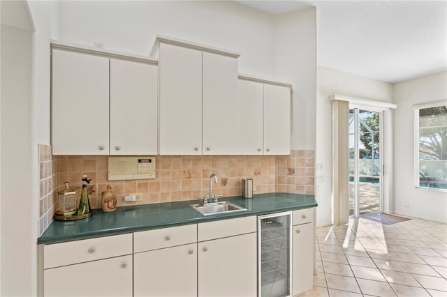 kitchen featuring backsplash, beverage cooler, sink, light tile patterned floors, and white cabinetry