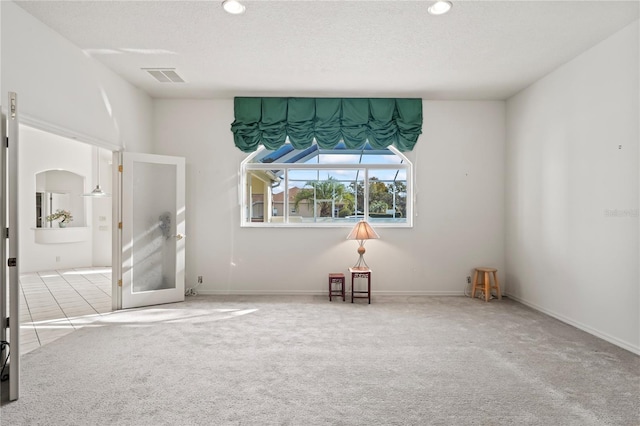 carpeted empty room featuring a textured ceiling