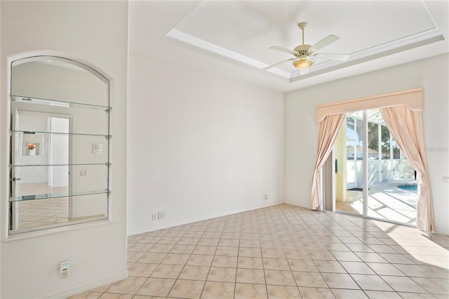 spare room with ceiling fan, a raised ceiling, and light tile patterned floors