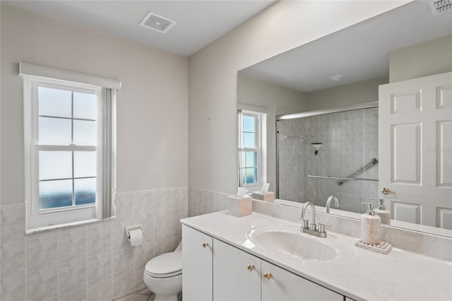 bathroom featuring a tile shower, vanity, toilet, and tile walls