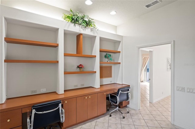 tiled home office with built in desk and a textured ceiling