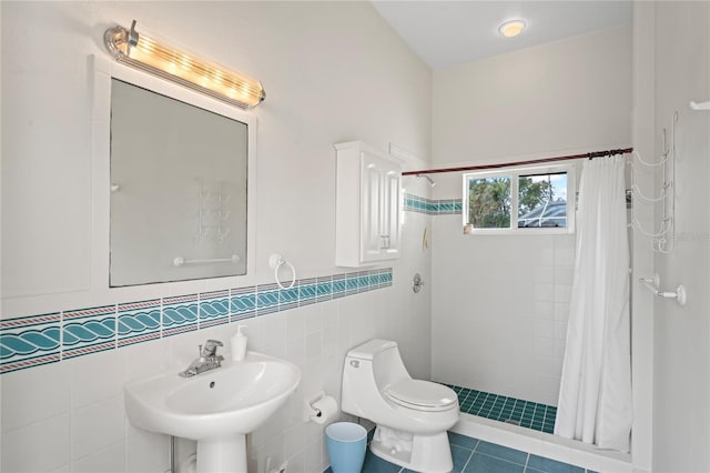 bathroom featuring tile patterned floors, sink, a shower with shower curtain, toilet, and tile walls