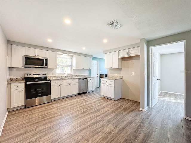 kitchen featuring sink, white cabinets, stainless steel appliances, and light wood-type flooring