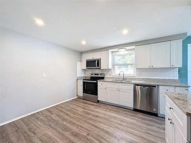 kitchen featuring white cabinets, stainless steel appliances, light hardwood / wood-style flooring, and sink