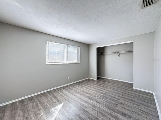 unfurnished bedroom with hardwood / wood-style flooring, a textured ceiling, and a closet