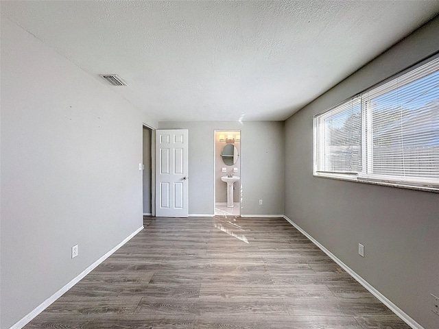 unfurnished room with a textured ceiling and hardwood / wood-style flooring