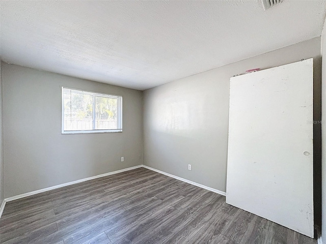 unfurnished room featuring a textured ceiling and dark wood-type flooring