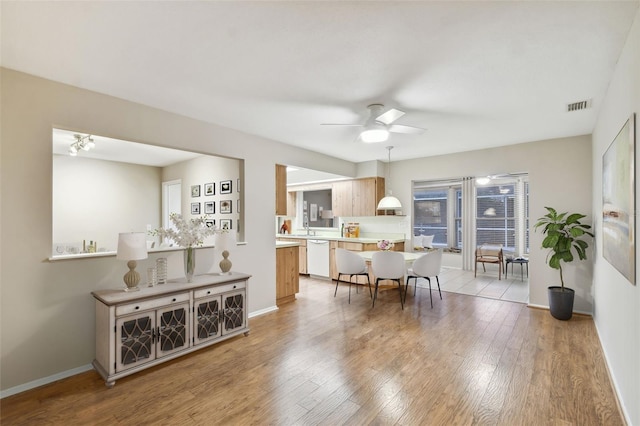 dining space featuring visible vents, a ceiling fan, baseboards, and light wood-type flooring