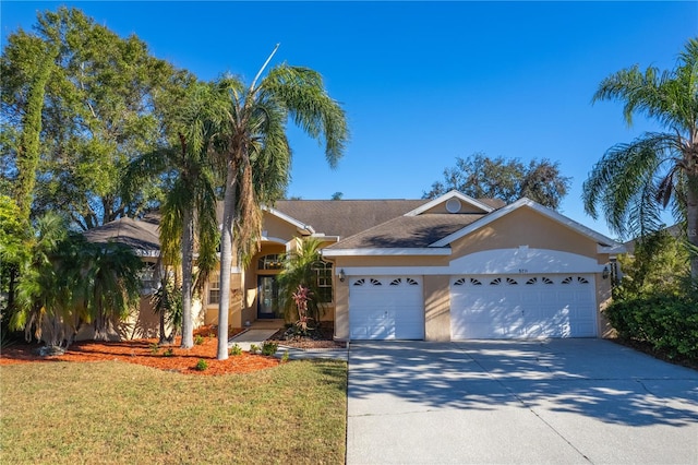 5211 Karlsburg Pl, Palm Harbor, FL 34685 - view of front facade featuring stucco siding, an attached garage, concrete driveway, and a front lawn