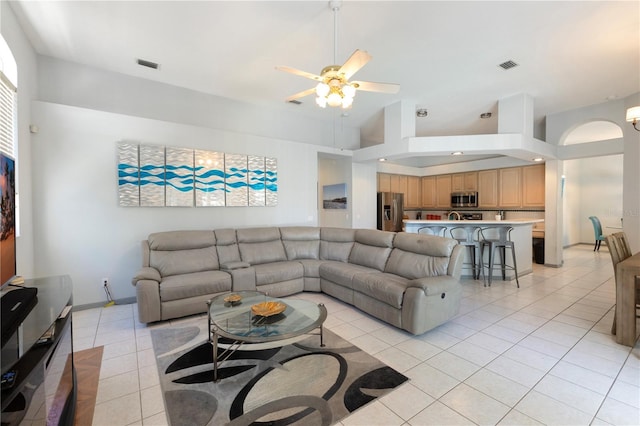 living room featuring ceiling fan, a towering ceiling, and light tile patterned floors