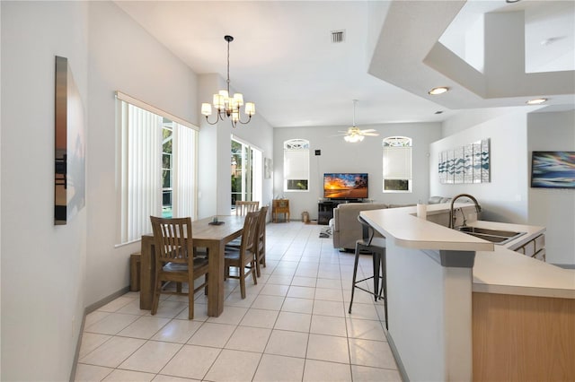 tiled dining area featuring ceiling fan with notable chandelier, a fireplace, and sink