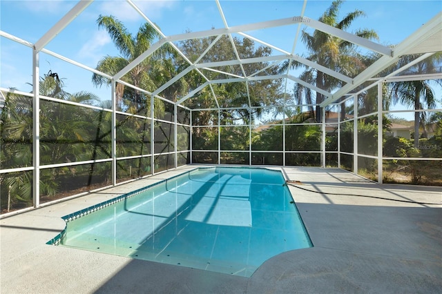 view of swimming pool featuring glass enclosure and a patio