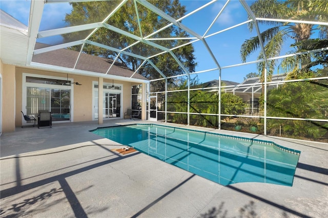 view of pool featuring glass enclosure, ceiling fan, and a patio