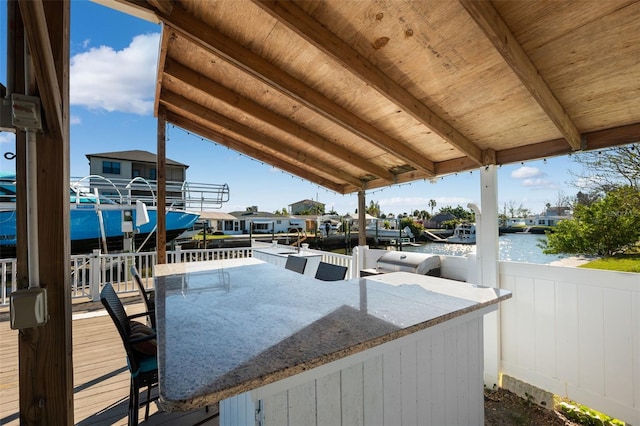 wooden terrace featuring a water view and a bar