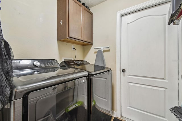 washroom featuring washer and dryer, a textured ceiling, and cabinets