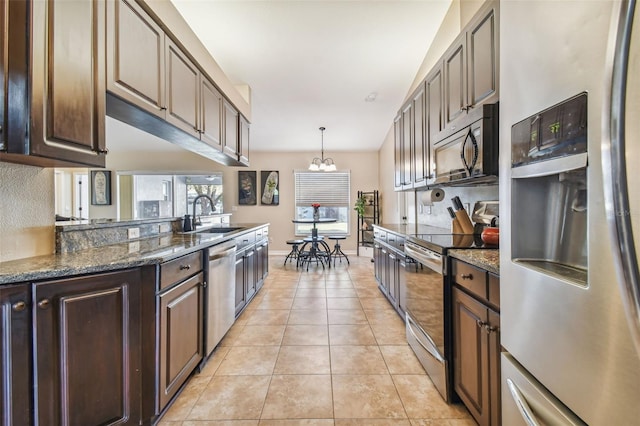 kitchen featuring sink, dark brown cabinetry, stainless steel appliances, and dark stone counters