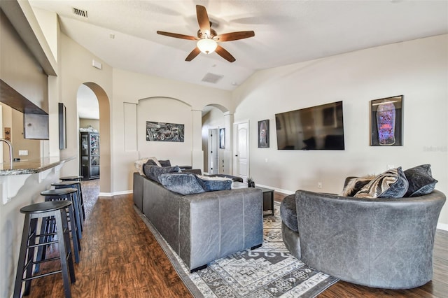 living room featuring ceiling fan, dark hardwood / wood-style flooring, and vaulted ceiling