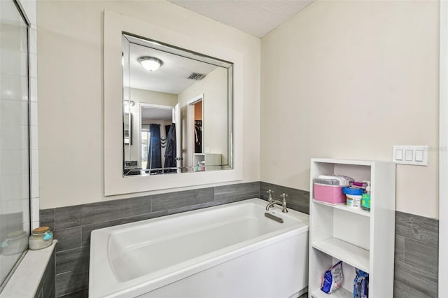 bathroom with tile walls, a bathtub, and a textured ceiling