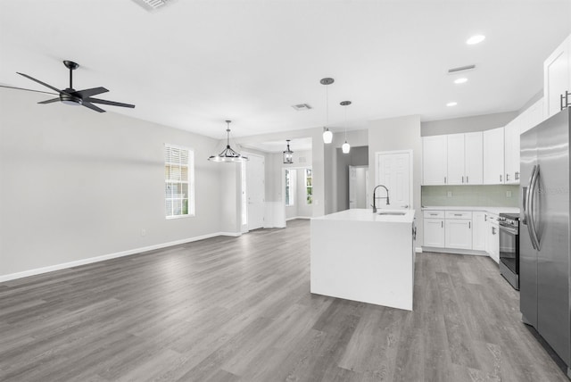 kitchen featuring white cabinets, hanging light fixtures, an island with sink, dark hardwood / wood-style flooring, and stainless steel appliances