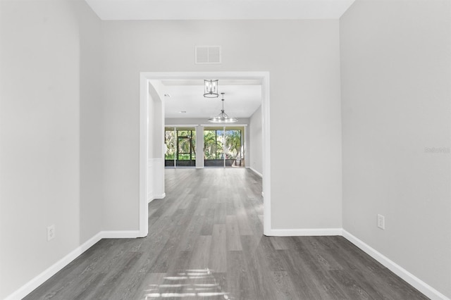 corridor with dark wood-type flooring and a notable chandelier