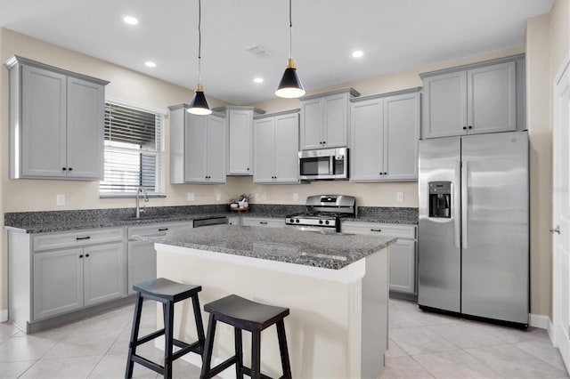 kitchen featuring appliances with stainless steel finishes, dark stone counters, a kitchen island, and pendant lighting