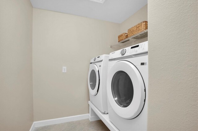 laundry area featuring washer and clothes dryer and light tile patterned flooring