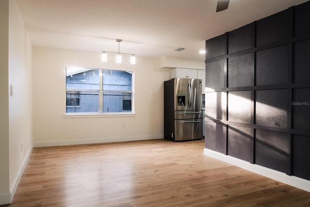 kitchen featuring hanging light fixtures, stainless steel fridge with ice dispenser, light wood-type flooring, a textured ceiling, and white cabinetry