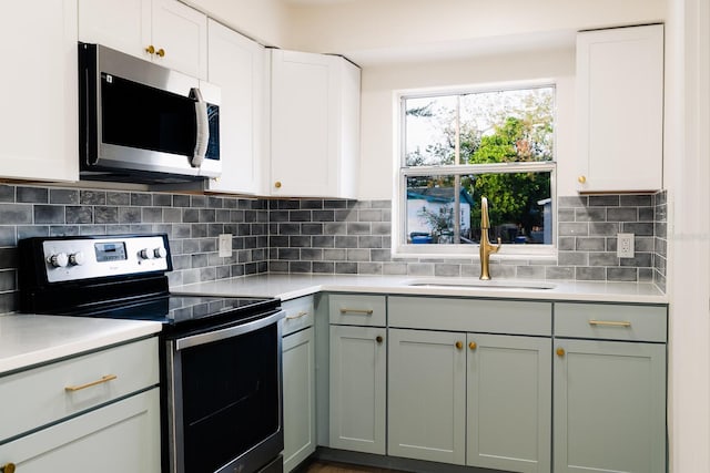 kitchen featuring white cabinets, backsplash, sink, and appliances with stainless steel finishes