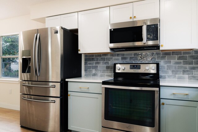 kitchen with tasteful backsplash, white cabinetry, and stainless steel appliances