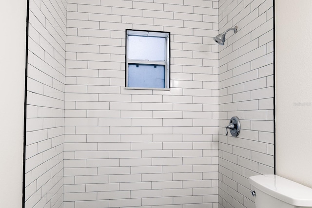 bathroom featuring tiled shower and toilet