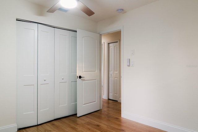 unfurnished bedroom featuring ceiling fan, light wood-type flooring, and a closet