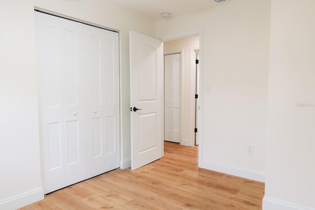 unfurnished bedroom with light hardwood / wood-style floors and a closet