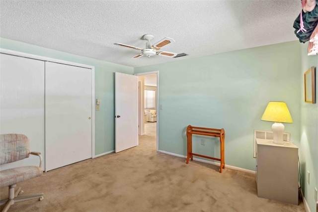 unfurnished bedroom with ceiling fan, light colored carpet, a textured ceiling, and a closet