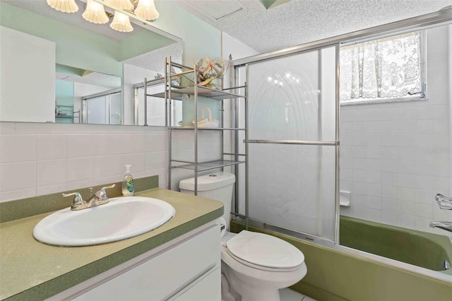 full bathroom featuring vanity, combined bath / shower with glass door, decorative backsplash, toilet, and a textured ceiling