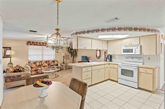 kitchen featuring sink, kitchen peninsula, a textured ceiling, decorative light fixtures, and white appliances